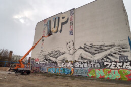Weite Ansicht der Fassade mit 1UP x Fanakapan ‘1UP’ Bubble-Lettern; Hebebühne im Einsatz, urbanes Umfeld im Vordergrund.