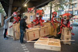 Herakut beim Aufbau einer großformatigen Skulptureninstallation im öffentlichen Raum mit Holzkisten.