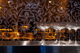 Cocktailgläser an der Bar im Fredericks Berlin vor der von LEITI gestalteten Glasfront.