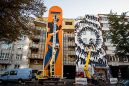 Zwei großformatige Urban-Art-Murals an Wohngebäuden, umgesetzt mit Hebebühnen im laufenden Stadtbetrieb.