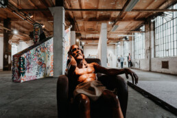 Skulptur einer sitzenden Figur in einer Ausstellungshalle mit Graffiti und Kunstinstallationen beim Monumenta Festival Leipzig 2018.