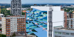 Weitblick auf das fertige Mural am MWG Forum in Magdeburg: grossflaechige, abstrakte Formen und die Schrift „FORUM MWG“ an der neuen Hauptzentrale.