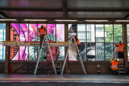 Montage einer großformatigen Kunstinstallation mit bedruckten Fensterfolien im U-Bahnhof Nollendorfplatz in Berlin.