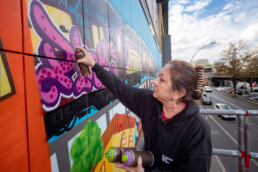 Lady Pink setzt mit Spraydosen einen Schriftzug auf der Museumsfassade