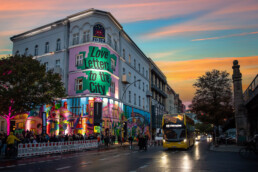 URBAN NATION Museumsfassade mit „Love Letters to the City“ und farbigem City-Motiv von Lady Pink bei Abendlicht.