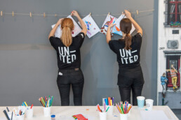 Team hängt Kinderzeichnungen im Workshop auf – Urban Nation Monster Project bei URBAN NATION.