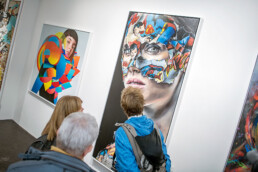 Besuchende betrachten gerahmte Kunstwerke bei der Urban Nation Museum Eröffnung 2017.