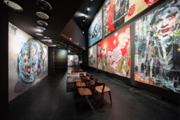 Galerieblick im Untergeschoss des Urban Nation Museums mit großformatigen Urban-Art-Werken und Sitzreihe (Museumsshow 2018)