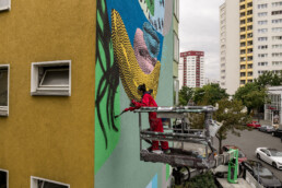 Künstlerteam auf der Hebebühne beim Ausarbeiten von Flächen und Konturen am One Wall Mural