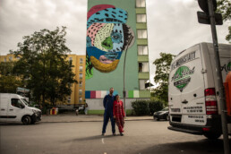 Straßenszene mit fertigem One Wall Mural von Various & Gould – Urban Nation, Berlin.
