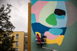 W.I.P.-Gesamtansicht: Various & Gould arbeiten auf der Hebebühne am großflächigen One Wall Mural für Urban Nation in Berlin.