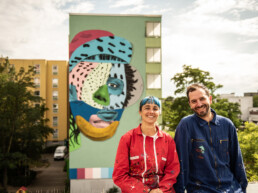 Porträt von Various & Gould vor dem fertigen One Wall Mural für Urban Nation in Berlin.