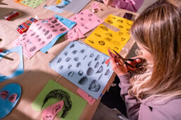 Workshop-Tisch mit Collage-Elementen (Augen, Münder) im Rahmen des Urban Nation One Wall Projekts von Various & Gould.