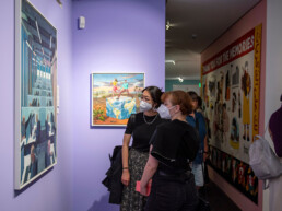 Besucher:innen betrachten Werke von Broken Fingaz und Interesni Kazki in der Ausstellung „Talking and other banana skins“ im Urban Nation Museum.