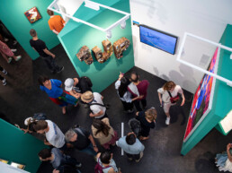 Blick von oben in die Ausstellung „Talking and other banana skins“ mit 1UP-Installation an der Wand im Urban Nation Museum.