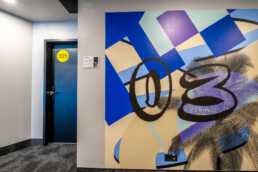 Hotelflur im Vienna House Easy by Wyndham Berlin mit großformatiger Wandgestaltung als Lift-Landing by Hundertzehn