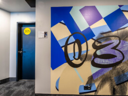 Hotelflur im Vienna House Easy by Wyndham Berlin mit großformatiger Wandgestaltung als Lift-Landing by Hundertzehn