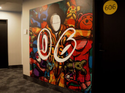 Hotelflur im Vienna House Easy by Wyndham Berlin mit großformatiger Wandgestaltung als Lift-Landing by Ron Miller