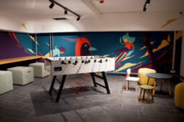 Lounge- und Spielbereich im Vienna House Easy by Wyndham Berlin mit illustrativer Wandgestaltung von Alex Hanke
