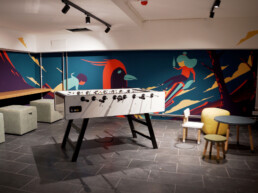 Lounge- und Spielbereich im Vienna House Easy by Wyndham Berlin mit illustrativer Wandgestaltung von Alex Hanke