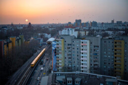 Brave Wall: Stadtblick bei Sonnenuntergang mit Voronina-Mural am Hochhaus entlang der U-Bahn-Trasse.