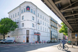 Aufbau der Museumsfassade von Broken Fingaz Crew am URBAN NATION Museum, Gesamtansicht mit Hebebühne und Straße