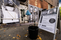 Infoständer „Photobooth Berlin Inside Out“ vor Gerüst und montierten Porträtflächen, Eimer und Material am Boden.