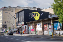 Gesamtansicht der KitKat Club Fassade in Berlin: Back Market Bespielung mit Vikunia-Motiv auf schwarzem Hintergrund.