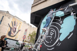 Vikunia-Motiv entsteht am KitKat Club Berlin: Malprozess auf Leiter, schwarze Fläche mit hellblauen Formen und Konturen.