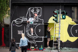 Malprozess am KitKat Club Berlin: Team arbeitet an grossflächigem Vikunia-Motiv für Back Market, Leitern und Farbeimer.