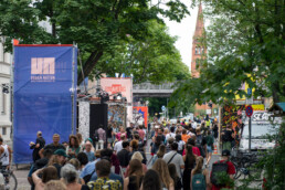 Viele Besucher auf der Straße zwischen Urban-Nation-Bannern und Festivalinstallationen beim UN-ARTIG Festival.