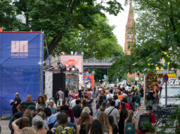 Viele Besucher auf der Straße zwischen Urban-Nation-Bannern und Festivalinstallationen beim UN-ARTIG Festival.