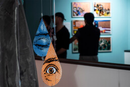 Hängende tropfenförmige Objekte mit Punktmuster und Augenmotiv in der Ausstellung „Talking and other Banana Skins“ im URBAN NATION Museum.