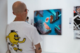 Person betrachtet ein großformatiges Werk aus THE VERSUS PROJECT von Layer Cake bei URBAN NATION.