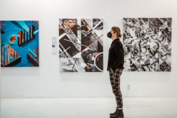 Besucher in der URBAN NATION Ausstellung vor mehreren Arbeiten aus THE VERSUS PROJECT von Layer Cake.