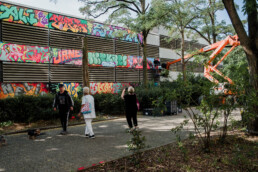 Blick auf die ONE WALL von Lukas Zeilinger am Parkhaus in Berlin Staaken mit Menschen aus dem Kiez vor der bemalten Fassade