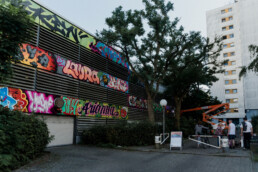Großformatiges Mural von Lukas Zeilinger am Parkhaus am Blasewitzer Ring in Berlin Staaken mit Hebebühne und Wohnhaus im Hintergrund
